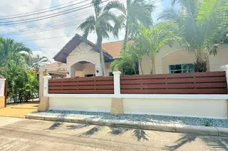 Mike Orchid Villas 2 house exterior with a modern fence, palm trees, and a tiled roof under a sunny sky.