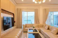 5 Bedroom House for Sale in Huai Yai bright living room with cream leather sectional sofa, TV wall and gold chandelier