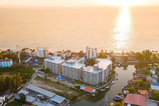 Whale Marina aerial view at sunset, showing buildings, river, and ocean with golden reflections.