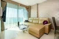 1 Bedroom Condo for Sale at Riviera Wong Amat Beach living room with beige leather L-shaped sofa and floor-to-ceiling sea view windows