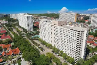 View Talay 2 aerial view of white condo buildings, parking lots, green trees, and Pattaya city skyline with ocean.