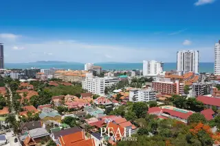 View Talay 2 aerial view of white condo buildings, parking lots, lush green trees, and Pattaya city skyline.