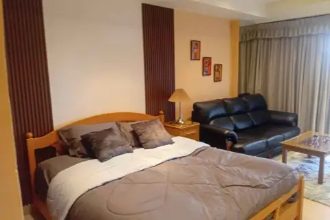Studio Condo for Rent at View Talay 5D bedroom with wooden bed frame, sofa, and wall art decor