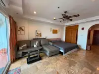Studio Condo for Sale at View Talay 5D living area with grey sectional sofa, bed, and wooden wardrobe
