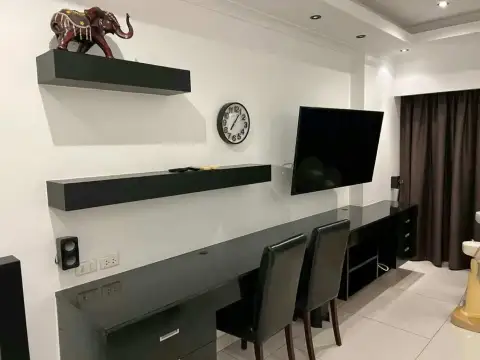 Studio Condo for Rent at View Talay 8 living area with mounted TV, floating shelves, desk and leather chairs