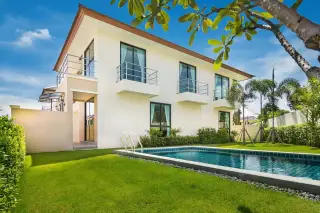 Villa Asiatic two-story white house with balconies, private swimming pool, and green lawn under a sunny sky.
