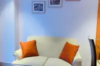 2 Bedroom Condo for Sale at The Senate Residences cream loveseat sofa with orange cushions and framed artwork on white wall