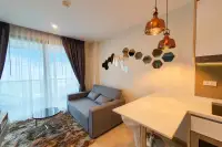 1 Bedroom Condo for Rent at The Riviera Jomtien open-plan living area with grey sofa, hexagon mirrors and copper pendant lights