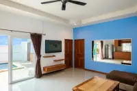 2 Bedroom House for Rent living room with a TV, ceiling fan, blue accent wall, and view of the pool through glass doors.