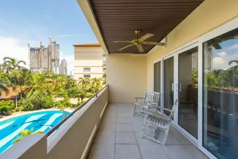 1 Bedroom Condo for Sale & Rent at View Talay Residence 1&2 private balcony with ceiling fan and wooden chairs overlooking the pool
