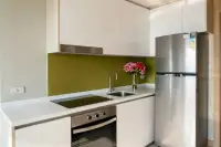 2 Bedroom Condo for Sale at The Riviera Jomtien: Modern kitchen with white cabinets, green backsplash, built-in oven, and stainless steel fridge.