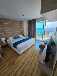 2 Bedroom Condo for Sale at Whale Marina master bedroom with king bed, wood flooring, and ocean view balcony