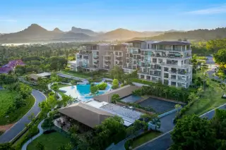 Sunplay Bangsaray: Aerial view of condo buildings, large swimming pool, lush landscaping, and mountains at sunset.