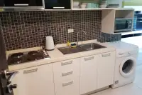 1 Bedroom Condo for Sale at Wongamat Privacy kitchen with electric hob, stainless steel sink, white cabinets, microwave, and washing machine