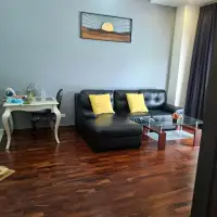 1 Bedroom Condo for Sale at Wongamat Privacy cozy living room with black sofa, yellow pillows, and wall art