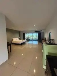 1 Bedroom Condo for Sale at Wongamat Privacy open-plan bedroom with king bed, tiled flooring and balcony access