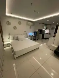 1 Bedroom Condo for Sale at Wongamat Tower bedroom with white bed frame and open kitchen in background