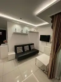 1 Bedroom Condo for Sale at Wongamat Tower living area with black leather sofa and wall-mounted TV