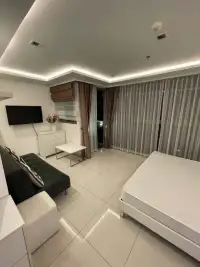 1 Bedroom Condo for Sale at Wongamat Tower bedroom and lounge area with sheer curtains and balcony access
