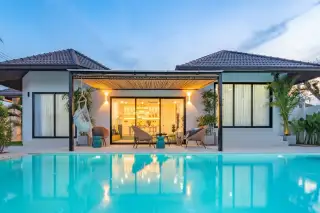 Srisuk Villa modern house exterior with private swimming pool, outdoor seating, and illuminated interior at dusk.