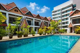 Corrib Village row of townhouses with traditional Thai-style gabled roofs and balconies under a blue sky.
