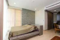 3 Bedroom Condo for Sale at Cetus Beachfront master bedroom with platform bed stone feature wall and floor-to-ceiling curtains