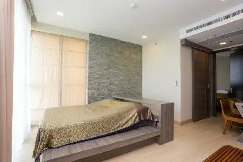 3 Bedroom Condo for Sale at Cetus Beachfront master bedroom with platform bed stone feature wall and floor-to-ceiling curtains