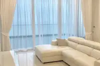3 Bedroom Condo for Sale at Del Mare white leather L-shaped sofa with sheer floor-to-ceiling curtains and sea view beyond