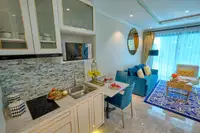 1 Bedroom Condo for Sale at Seven Seas Le Carnival: kitchen area with white cabinets, sink, and dining table next to living room.