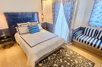 Studio Condo for Sale at Seven Seas Cote d'Azur: Bedroom with bed, blue and white striped sofa, and patterned curtains.