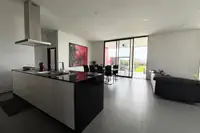 3 Bedroom House for Sale at The Prestige at Siam Royal View: Open-plan living area with kitchen island, dining table, and sofa, opening to the patio.