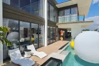 4 Bedroom House for Sale at Highbury Hill Pool Villas Pattaya poolside timber deck with sun loungers and floor-to-ceiling glass facade