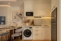 1 Bedroom Condo for Sale at Seaspire Jomtien compact white kitchen with marble backsplash, built-in microwave, washer, and dining table