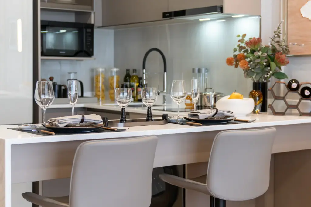 1 Bedroom Condo for Sale at Aquarous Jomtien Pattaya kitchen island with white countertop bar stools and wine glasses