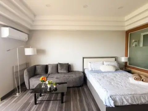 Studio Condo for Sale at Jomtien Condotel & Village studio layout with bed, TV console, and wood flooring