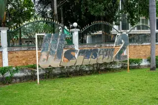 Phonthep Garden Ville 2 reflective metal Thai script signage on brick wall with green lawn and ornamental fence