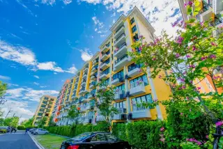 Venetian Signature Condo Resort exterior view of yellow residential tower with balconies and flowering trees