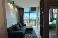 2 Bedroom Condo for Sale at The Twin Tower Jomtien Beach Pattaya living room with L-shaped sofa and floor-to-ceiling windows overlooking Pattaya city