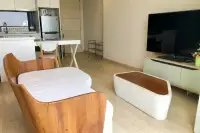 1 Bedroom Condo for Sale at Cetus Beachfront open-plan living and dining area with wooden armchair and kitchen beyond