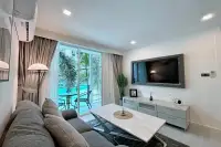 1 Bedroom Condo for Sale at City Center Residence living room with wall-mounted TV marble coffee table and pool-facing balcony