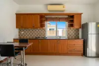 2 Bedroom House for Rent kitchen with wooden cabinets, a stainless steel refrigerator, and dining table with chairs.