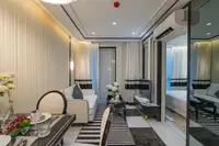 1 Bedroom Condo for Sale at Embassy Life living area with sofa, dining table, and mirrored partition to bedroom.