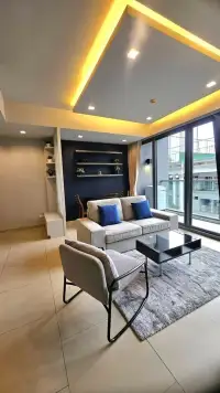 1 Bedroom Condo for Sale at Zire Wongamat living room with sofa, armchair, and glowing ceiling light feature