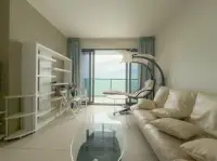 1 Bedroom Condo for Sale at Zire Wongamat living room with cream sofa and ocean view balcony