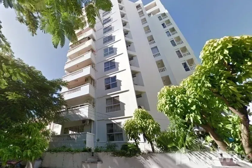 Pattaya Tower condo building exterior with multiple balconies and surrounding green trees under a clear blue sky.