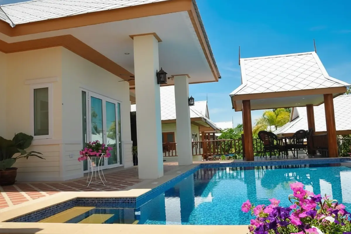 Amorn Village house exterior showing a swimming pool, a covered patio with columns, and a traditional Thai gazebo.