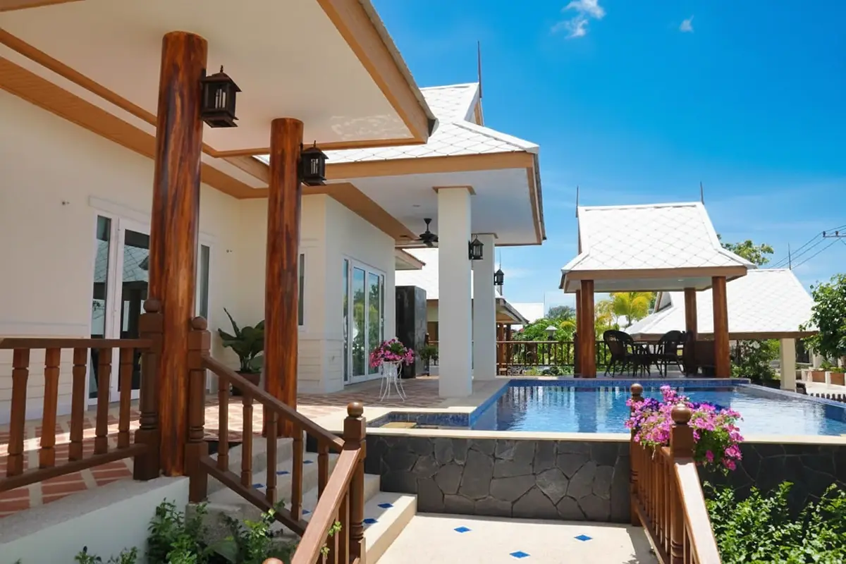 Amorn Village exterior with a swimming pool, wooden stairs, covered patio, and a traditional Thai style gazebo.