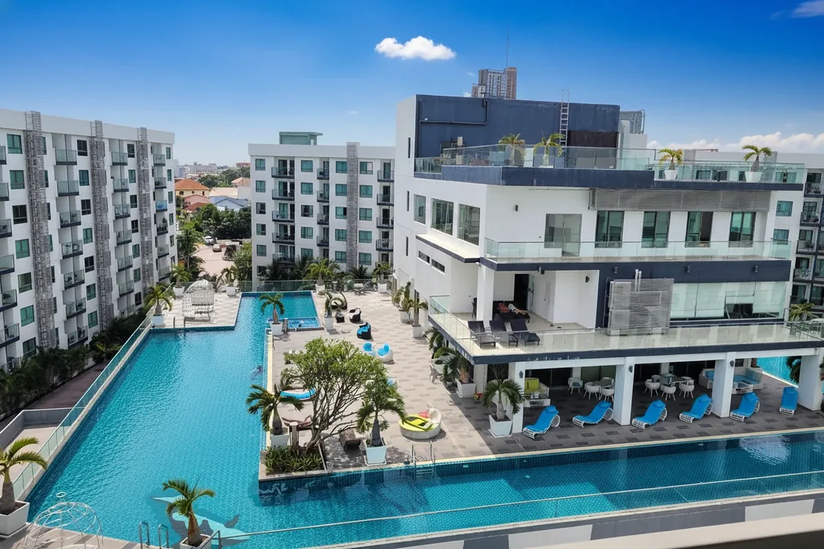 Arcadia Beach Resort main entrance sign with golden letters, lush greenery, and resort buildings in the background.
