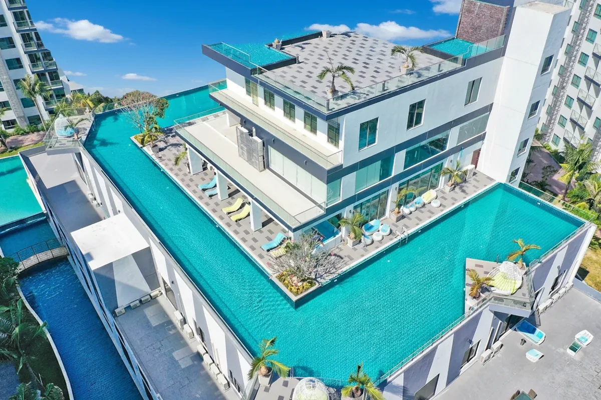 Arcadia Beach Resort expansive outdoor swimming pool area with sun loungers, surrounded by modern resort buildings.