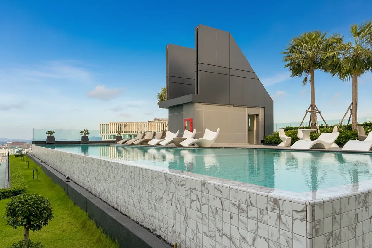 Arcadia Millennium Tower rooftop infinity pool with lounge chairs and palm trees, offering panoramic city views.